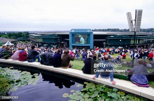 Spectators watch the Women's Singles Semi Final match between Jana Novotná and Martina Hingis on the big screen from their Henman Hill vantage...