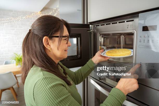 mujer cocinando comida en microondas - tortilla de patata fotografías e imágenes de stock