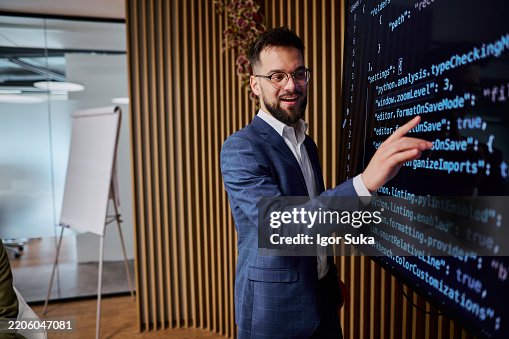 Software Developer Explaining Code on Digital Screen to Colleagues Software Developer Explaining Code on Digital Screen to Colleagues