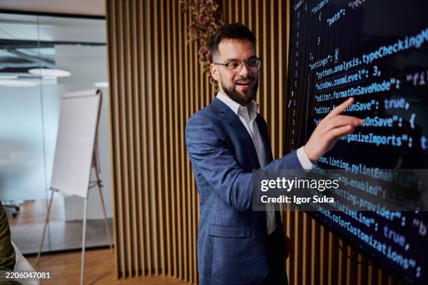 software developer explaining code on digital screen to colleagues - computer programmer stock pictures, royalty-free photos & images