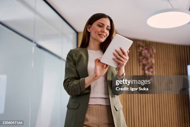 femme d’affaires utilisant une tablette numérique dans un bureau moderne - utiliser une tablette numérique photos et images de collection