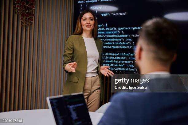 software developer presenting code on a monitor to her colleague during a business meeting - python programmeertaal stockfoto's en -beelden