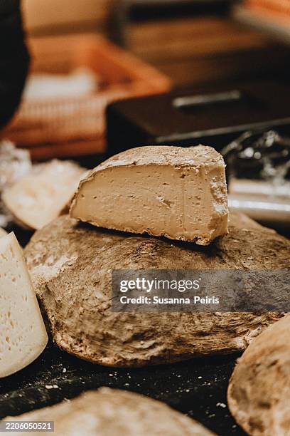 slice of rustic artisanal cheese displayed at local farmers market - queso español fotografías e imágenes de stock