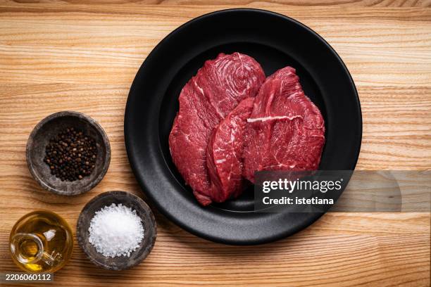 raw beef meat in black plate - chuck steak plate stock pictures, royalty-free photos & images