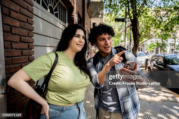 tourist couple using mobile phone on street - tonen stockfoto's en -beelden
