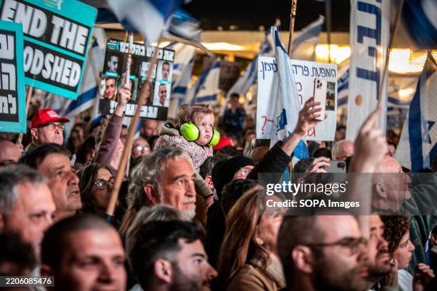 Protesters hold placards during a demonstration. Thousands of people demonstrated in Tel Aviv and other Israeli population centers against the...