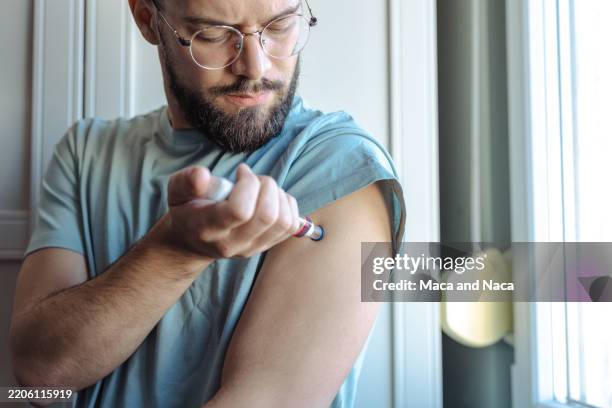 mann, der tagsüber in innenräumen eine injektion in den arm verabreicht - typ 1 diabetes stock-fotos und bilder