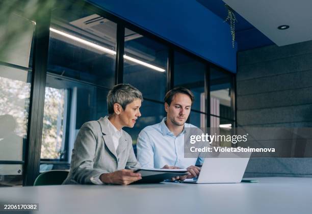 colleagues discussing project at workplace. - sitting stock pictures, royalty-free photos & images