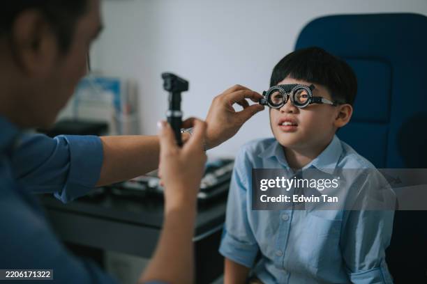 optometrista asiatico che fa un esame della vista con un ragazzo in clinica - miopia foto e immagini stock