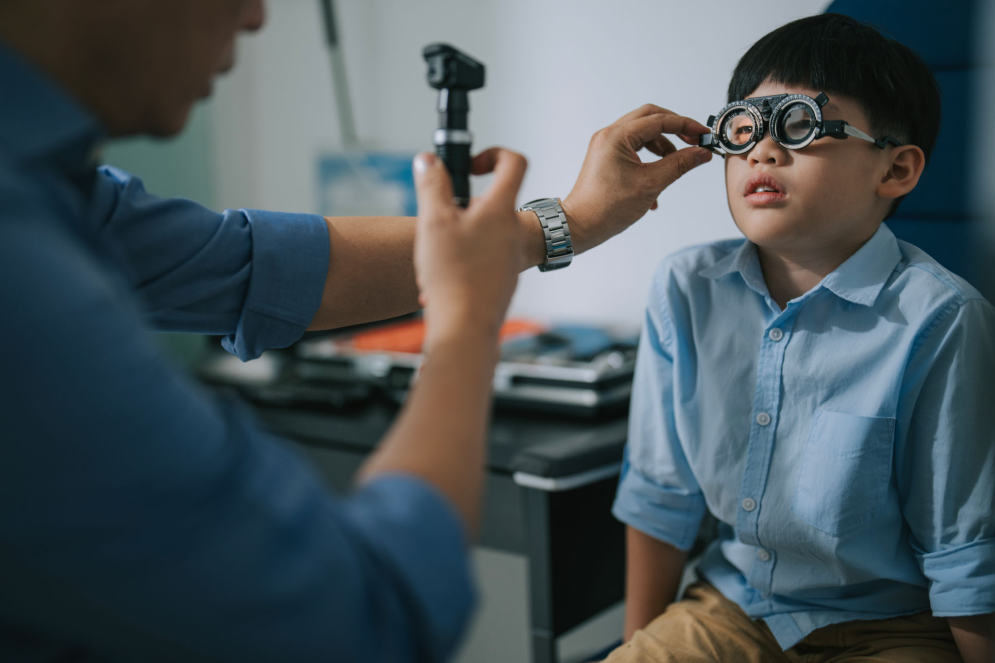 Asian optometrist doing eye test with a boy in clinic Asian optometrist doing eye test with a boy in clinic