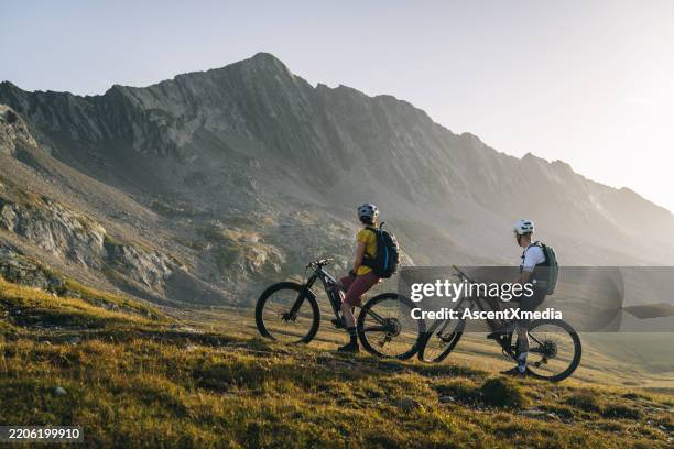 mountainbiker machen pause auf bergwiese - fahrrad fahren stock-fotos und bilder