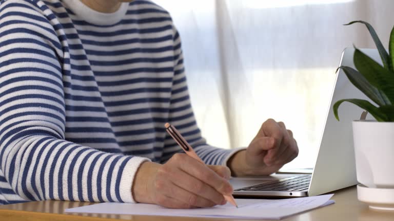 https://media.gettyimages.com/id/2206209479/video/a-womans-hand-writing-with-a-pen-while-working-on-a-laptop-the-person-is-wearing-a-striped.jpg?b=1&s=640x640&k=20&c=OarxvFuDxoBeN0YWA34AJdl8zpTLXOG2BpNXOCBCdLU=