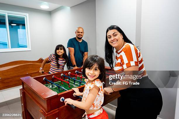portrait of a family playing foosball in a games room - games room stock pictures, royalty-free photos & images