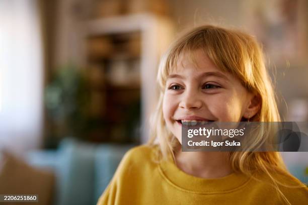 portrait of a smiling young girl missing a tooth looking away from the camera - portrait of a young girl with gappy teeth and blond hair stock pictures, royalty-free photos & images