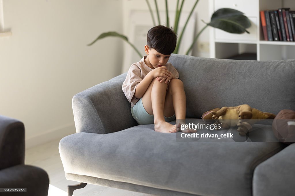 Criança problemática chateada sentada no sofá