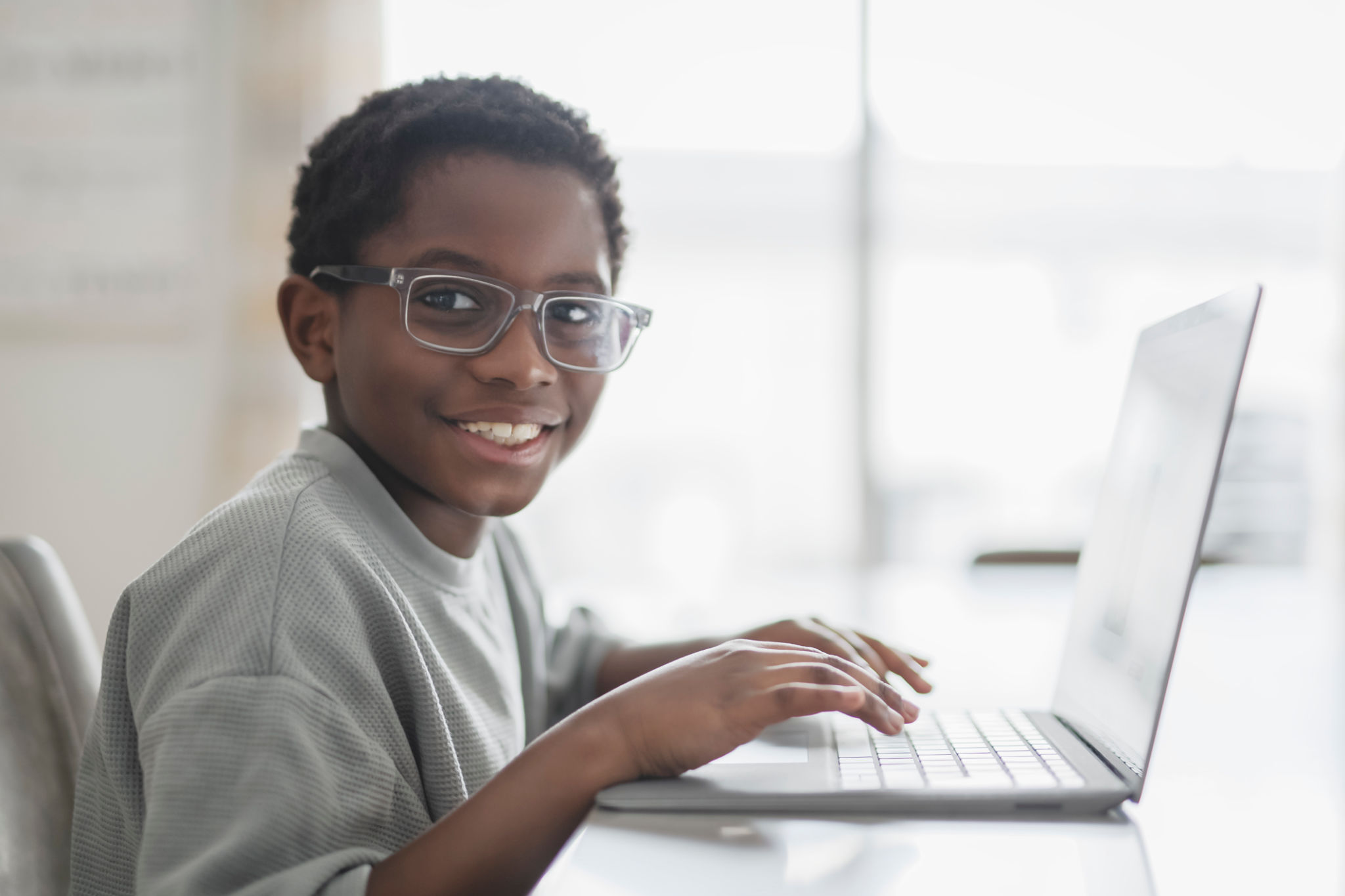 Little American boy studying online with laptop in kitchen Little American boy studying online with laptop in kitchen