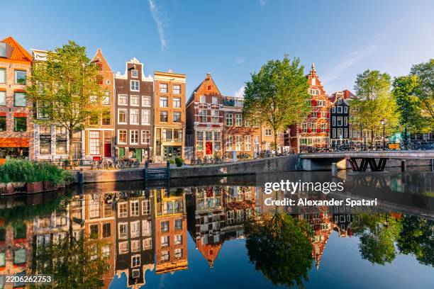traditional dutch houses along the canal on a sunny morning, amsterdam, netherlands - países bajos fotografías e imágenes de stock