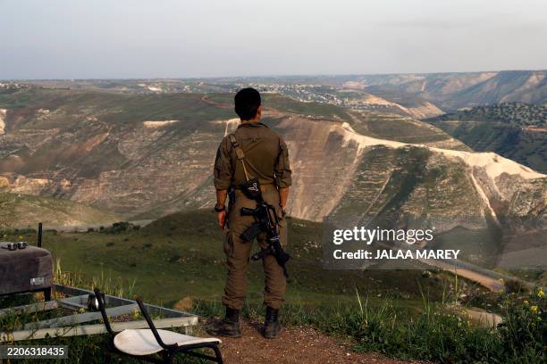 An Israeli soldier stands at a lookout point in the Israel-annexed Golan Heights overlooking south Syria, on March 25, 2025. Israel's military said...