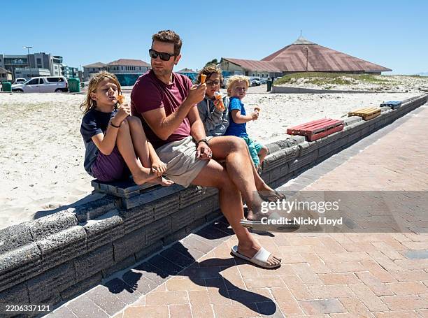 junger mann und kinder genießen eis am strand - boy and girl eating ice cream stock-fotos und bilder