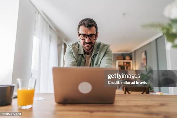 freelancer working from home using laptop at the table - green shirt stock pictures, royalty-free photos & images