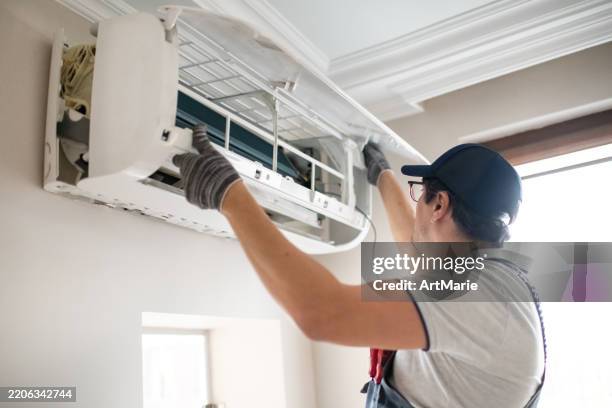 técnico reparando aire acondicionado a domicilio - aire acondicionado fotografías e imágenes de stock
