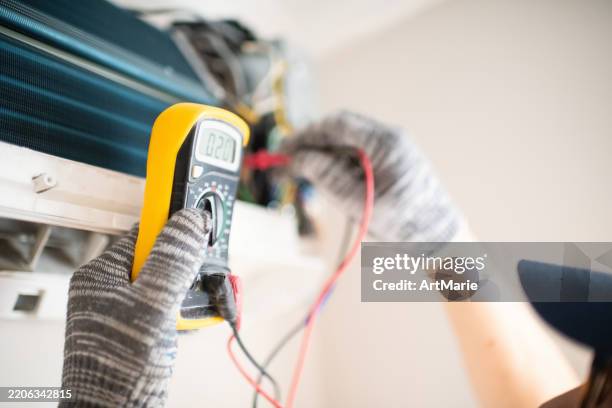 técnico con multímetro reparando aire acondicionado a domicilio - oficio en servicios fotografías e imágenes de stock