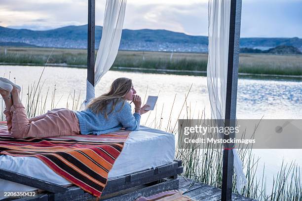 woman relaxing on outdoor bed by tranquil lake - sprawl 3rd world stock pictures, royalty-free photos & images