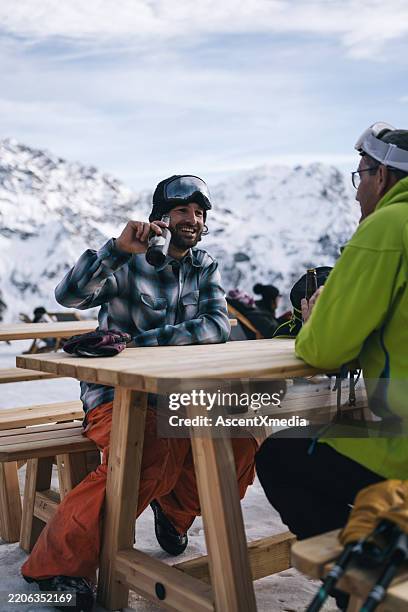 father and adult son enjoy beer at swiss ski resort - apres ski stockfoto's en -beelden