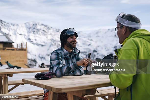 father and adult son enjoy beer at swiss ski resort - apres ski stockfoto's en -beelden