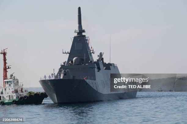 Tug boat pushes Japanese Maritime Self-Defence Force frigate JS Noshiro as it docks at the Naval Operating base of the Philippine navy in Subic town,...