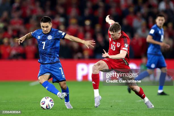 Serikzhan Muzhikov of Kazakhstan runs with the ball whilst under pressure from David Brooks of Wales during the FIFA World Cup 2026 European...