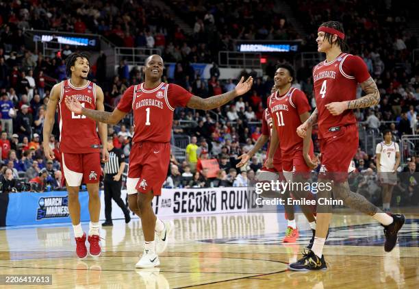 Johnell Davis and Trevon Brazile of the Arkansas Razorbacks celebrate with teammates after defeating the St. John's Red Storm with a score of 75 to...