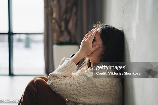 silhouette of sad and depressed woman sitting on the floor at home - culpabilidad fotografías e imágenes de stock