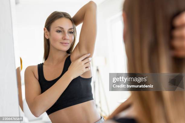 young woman looking at her armpit - oksel stockfoto's en -beelden