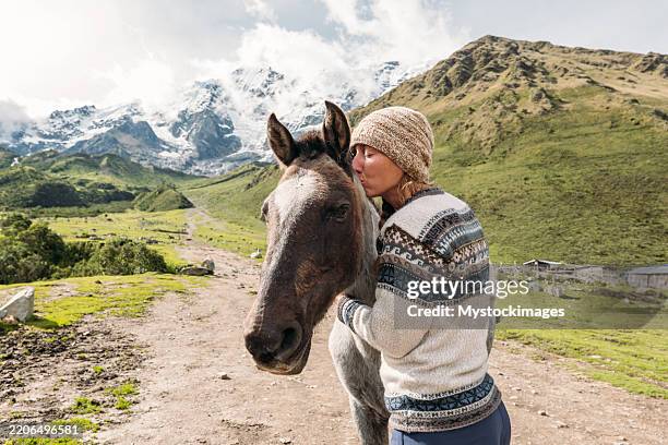 mujer abrazando caballo en paisaje de montaña - los andes fotografías e imágenes de stock