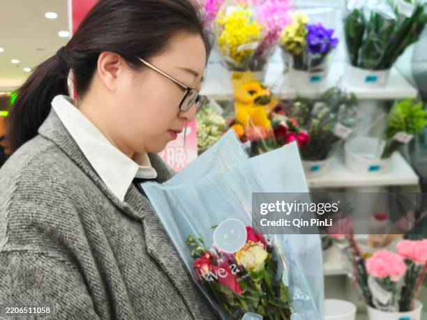 happy beautiful young woman in a flower shop and choosing flowers. the concept of gardening and flowers - interior design descriptive words stock pictures, royalty-free photos & images