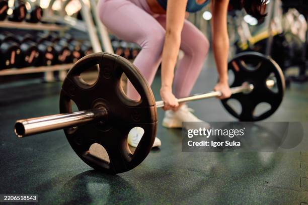 determined sportswoman lifting barbell in modern gym - anaerobic exercise stock pictures, royalty-free photos & images