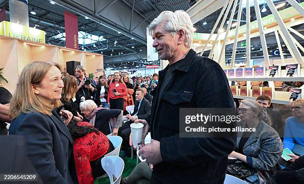 March 2025, Saxony, Leipzig: Laila Stenseng , Norwegian ambassador to Germany, talks to Karl Ove Knausgard, author from Norway, at the stand of the...