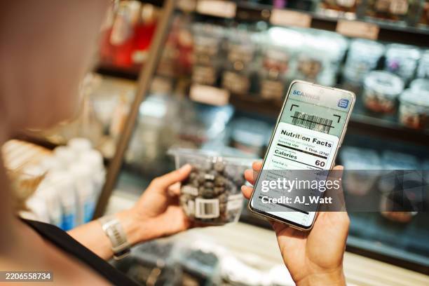 close-up of woman scanning barcode of product and reading nutrition details on smartphone - food labels stock pictures, royalty-free photos & images