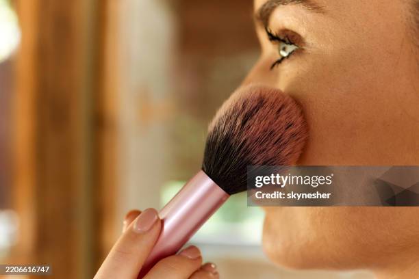 close up of a woman applying blush in the bathroom. - woman applying blush stock pictures, royalty-free photos & images