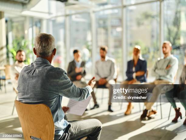 back view of a male coach leading a group therapy in the office. - group therapy stock pictures, royalty-free photos & images
