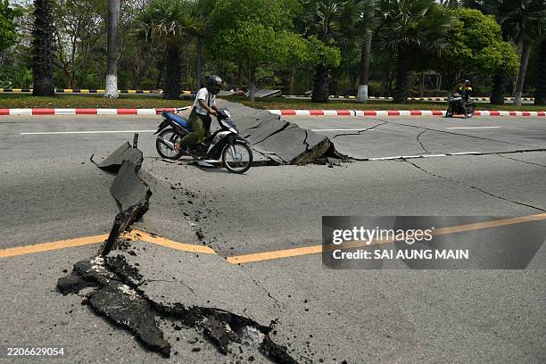 Motorcyclist rides past a damaged road in Naypyidaw on March 28 after an earthquake in central Myanmar. A powerful earthquake rocked central Myanmar...