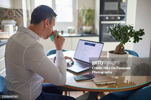 man browsing job listing on laptop at home - beginnings stock pictures, royalty-free photos & images