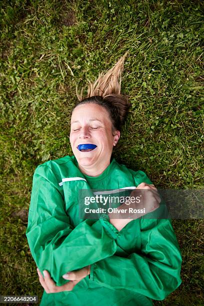 female rugby player with eyes closed lying on lawn - gum shield stock pictures, royalty-free photos & images