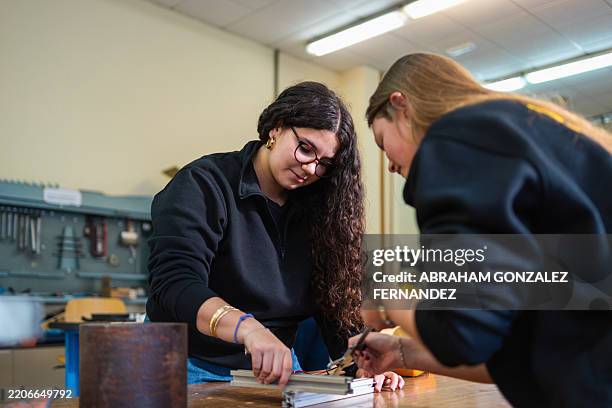 two young women working together on a project in a workshop, possibly engineering students - vocational education stock pictures, royalty-free photos & images