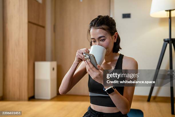 close-up shot of woman tracking her water intake on her smartphone while sipping from her glass to reach goal - data intake stock pictures, royalty-free photos & images