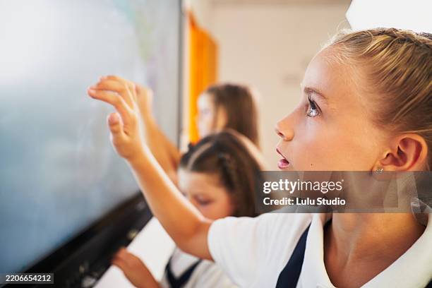 elementary school students interacting with interactive whiteboard in classroom - interactive whiteboard stock pictures, royalty-free photos & images