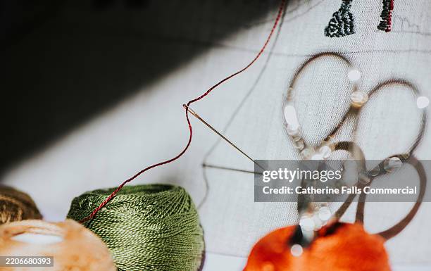 spools of silk perle thread on a wooden table in front of linen fabric beside a pair of small embroidery scissors - haberdashery stock pictures, royalty-free photos & images
