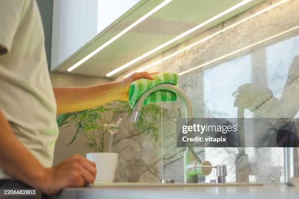 handreinigung wasserhahn mit grünem tuch in einer modernen küche - spültuch stock-fotos und bilder