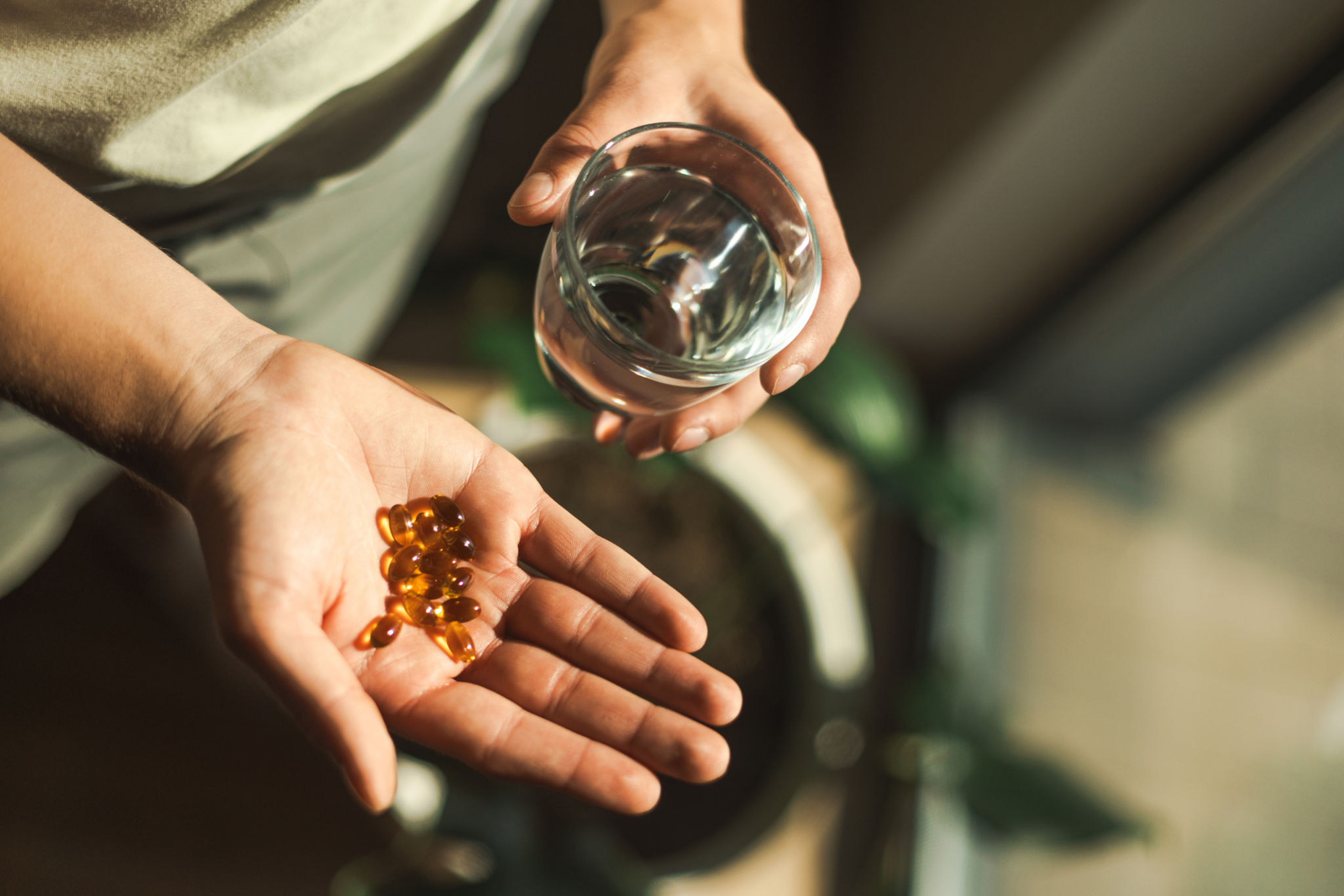 Close-Up of Hands Holding Pills and a Glass of Water Close-Up of Hands Holding Pills and a Glass of Water